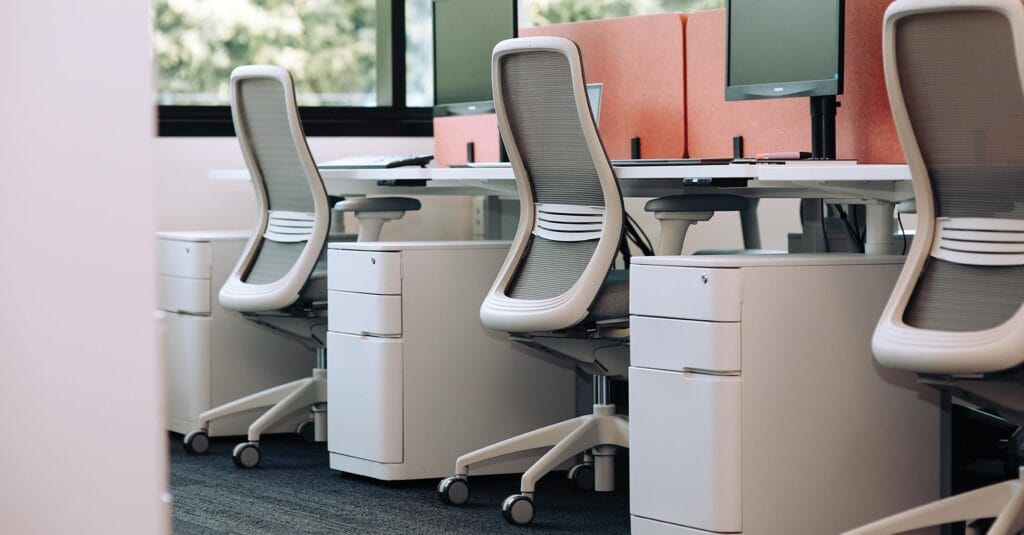 movement-friendly-workspace three ergonomic light grey desk chairs in office