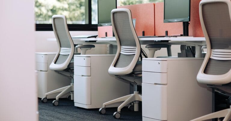 three ergonomic light grey desk chairs in office