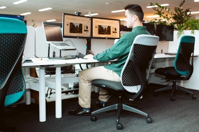 man working on computer sitting at ergonomic chair